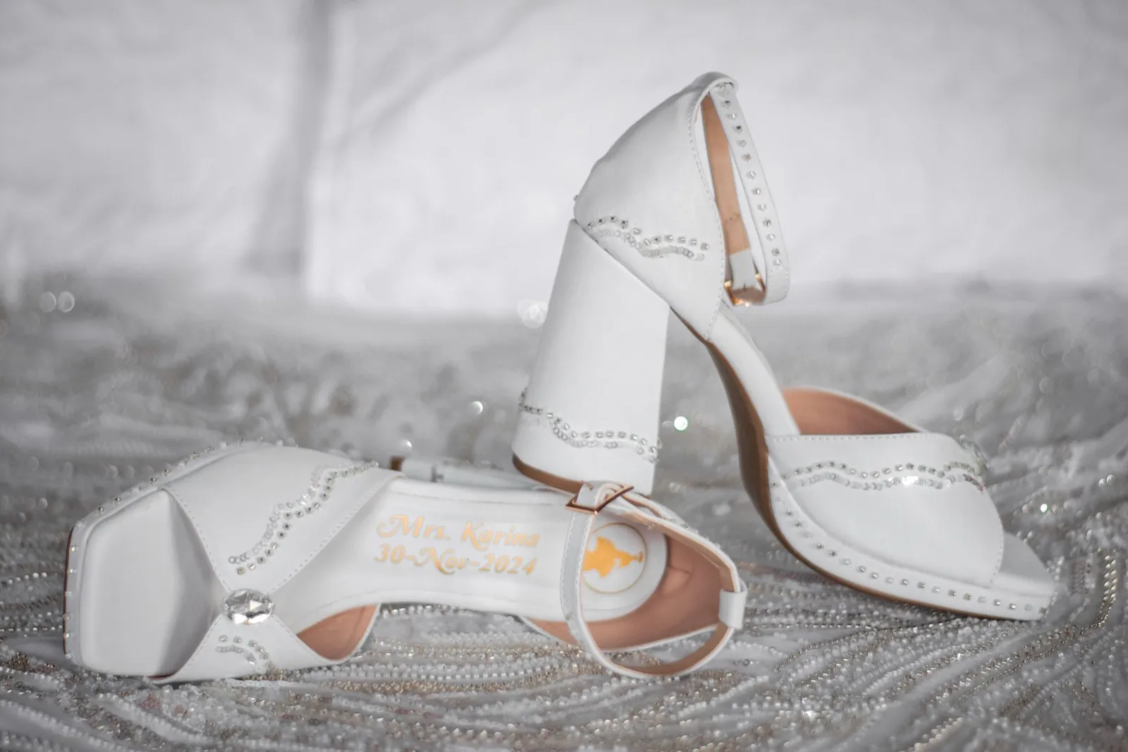Detalle de zapatos blancos sobre tela con pedrería